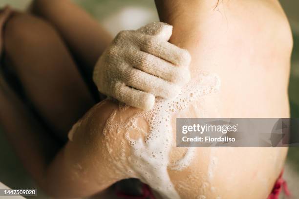washing massage glove with shower foam for washing the body in female hands. relaxation and beauty treatments. natural beauty, daily skincare routine. moisturizing, cleansing - corpo normale foto e immagini stock