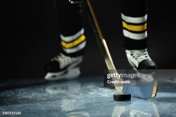 hockeyspieler in sportuniform und schlittschuhen stehend mit stock in den händen. - hockey background stock-fotos und bilder