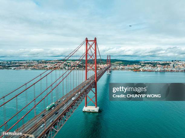 panoramic photograph of the 25 de abril bridge in the city of lisbon over the tajo river. - 25 de abril bridge stockfoto's en -beelden