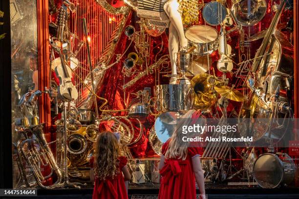 Two girls dressed in red holiday outfits look at the Bergdorf Goodman's Holiday windows on Fifth Avenue on December 07, 2022 in New York City.