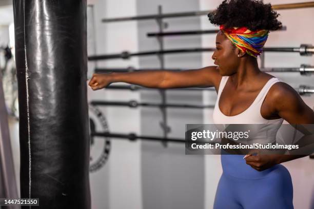 a female athlete of african-american ethnicity is punching a bag in a gym. - self defense stock pictures, royalty-free photos & images