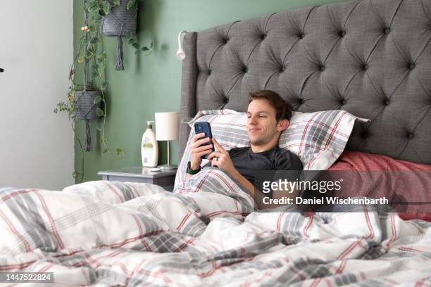 young man relaxing in bed - flannel stock pictures, royalty-free photos & images