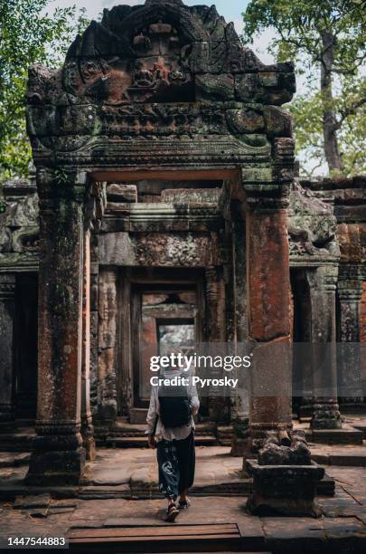 a man exploring the temples at the angkor wat complex - angkor wat bayon stockfoto's en -beelden