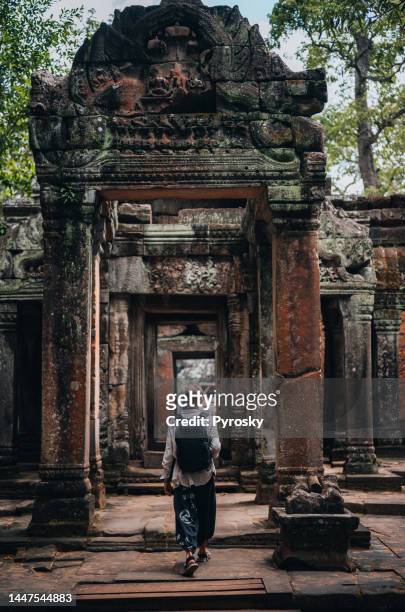a man exploring the temples at the angkor wat complex - angkor wat stock pictures, royalty-free photos & images