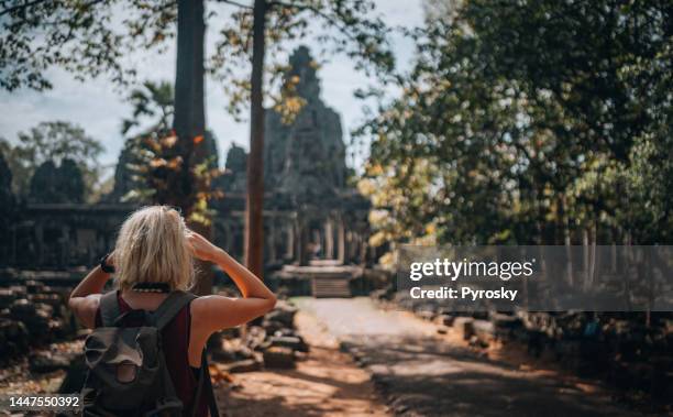 rear view of a woman admiring the temples - angkor wat bayon stockfoto's en -beelden