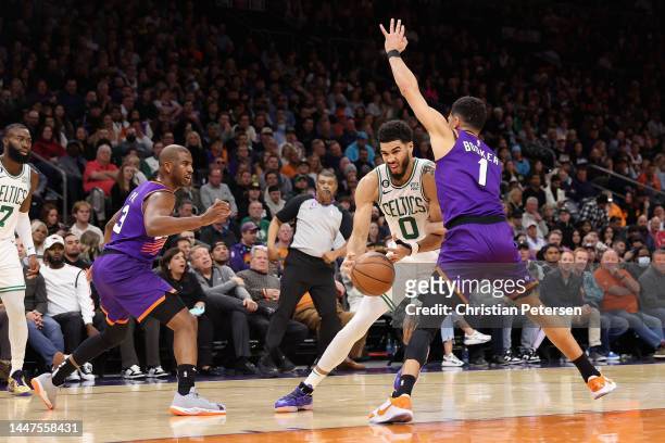 Jayson Tatum of the Boston Celtics drives the ball against Devin Booker of the Phoenix Suns during the first half of the NBA game at Footprint Center...