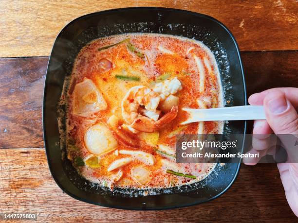 eating tom yum soup with seafood, personal perspective view - tom yum suppe stock-fotos und bilder