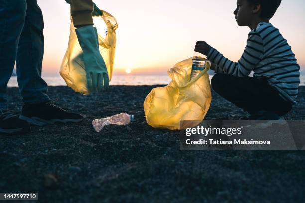 dad and son clean up trash on the beach at sunset. - father and children volunteering stock pictures, royalty-free photos & images