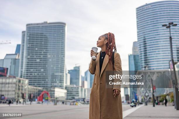 african lady walking around the city while holding her coffee - trench coat stock pictures, royalty-free photos & images
