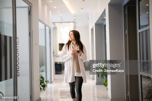 endodontist walking with mobile phone at the clinic - busy hospital lobby stockfoto's en -beelden