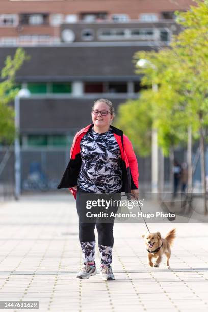 blonde girl with eyeglasses running with her dog down a city street. - cansado 個照片及圖片檔