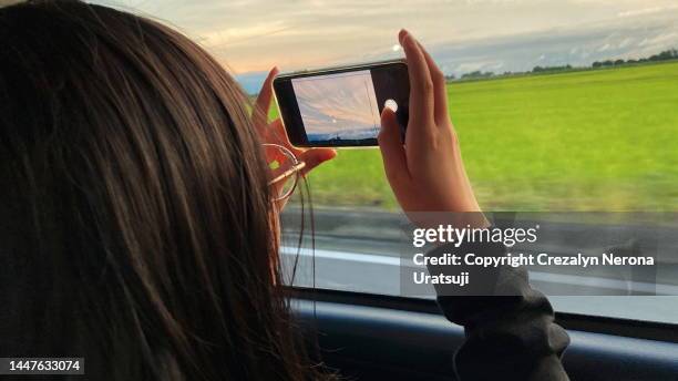 child learning how to take photo on smartphone while on the move. drive trip with mobile - rear view hand window stock pictures, royalty-free photos & images