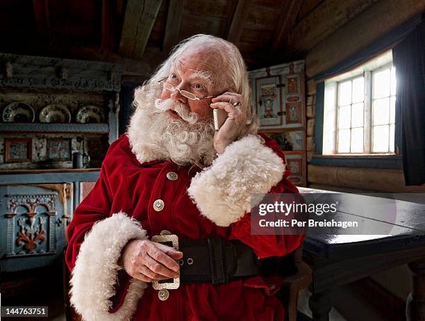 santa claus using his smart phone - papá noel fotografías e imágenes de stock