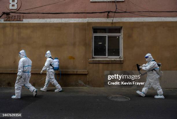 Epidemic control workers wear PPE as they sanitize outside a residential area where people are doing home quarantine on December 8, 2022 in Beijing,...