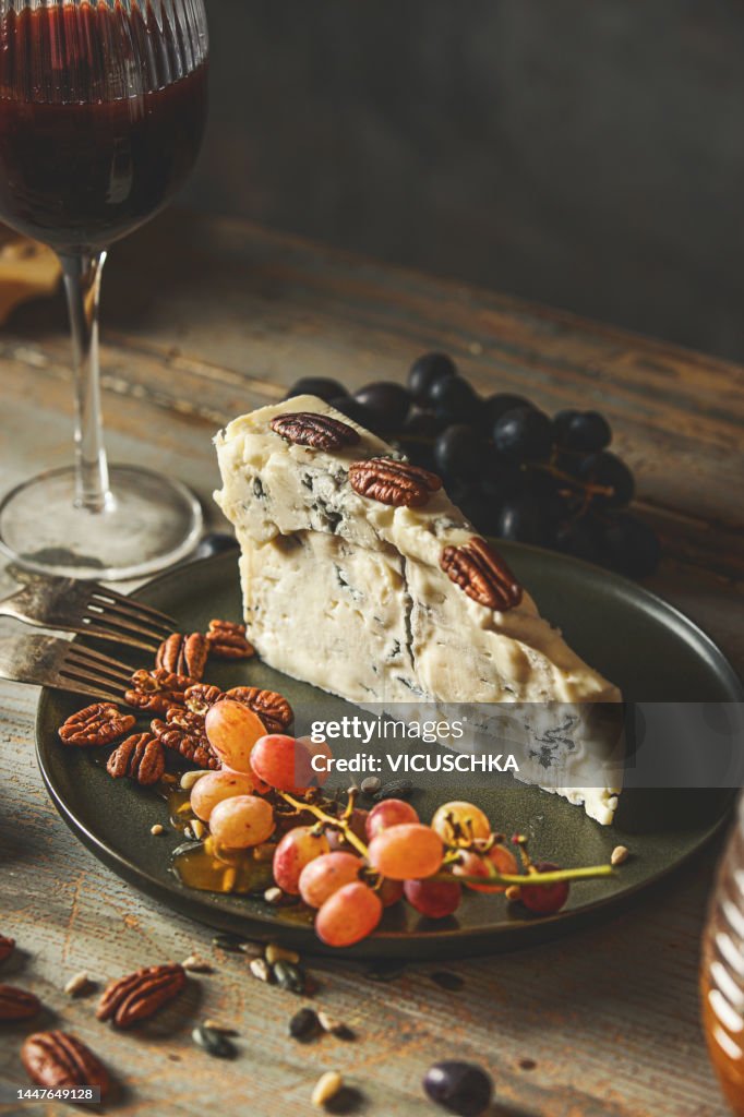 Piece of gorgonzola cheese with nuts, grapes and red wine