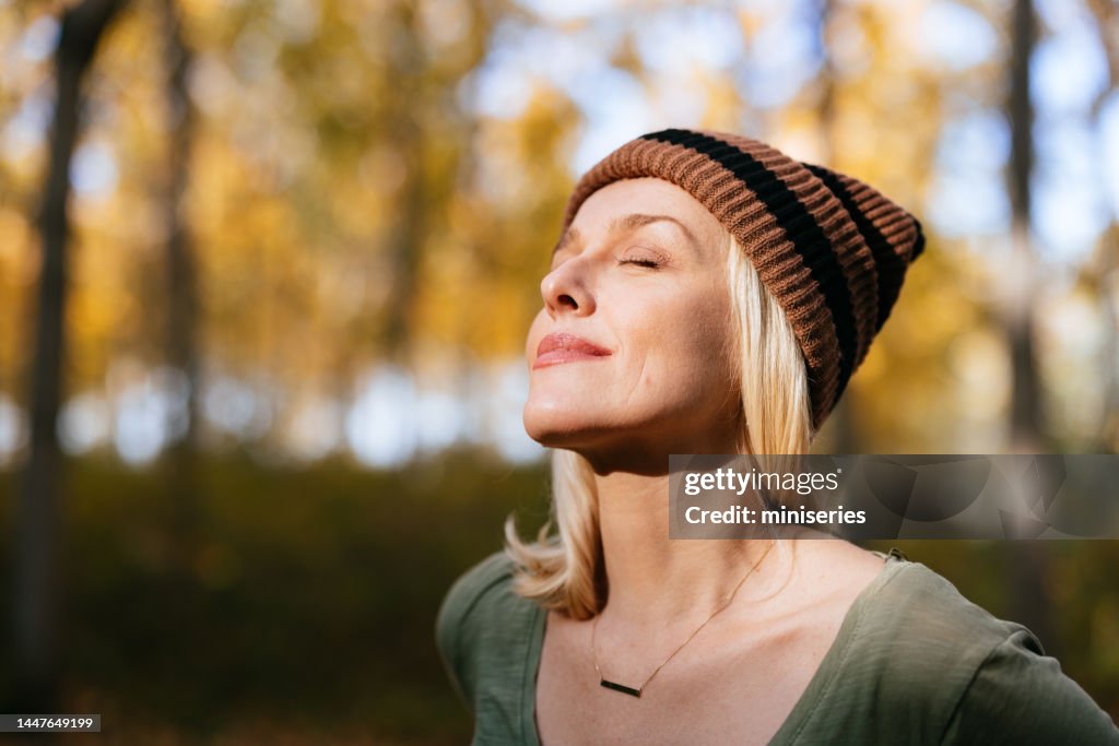 Porträt einer schönen Frau, die im Wald steht und das Sonnenlicht genießt