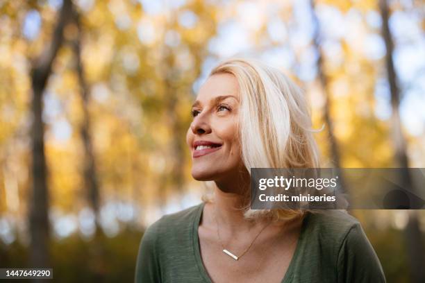 portrait of a beautiful woman standing in the woods enjoying the sunlight - face look right stock pictures, royalty-free photos & images