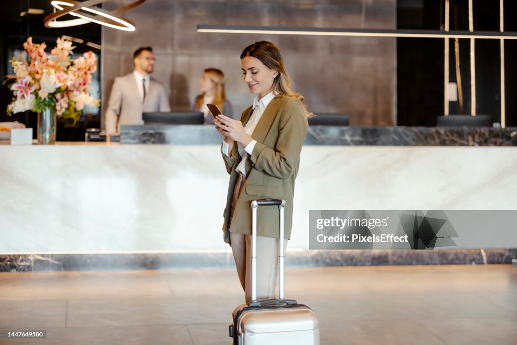 Geschäftsfrau auf Handy in der Hotellobby
