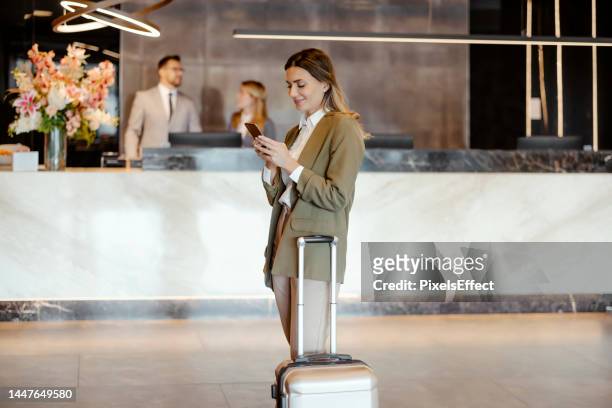 femme d’affaires sur téléphone portable dans le hall de l’hôtel - reception hotel photos et images de collection