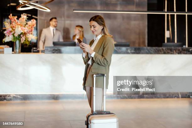 businesswoman on mobile phone in the hotel lobby - hotel reception stock pictures, royalty-free photos & images