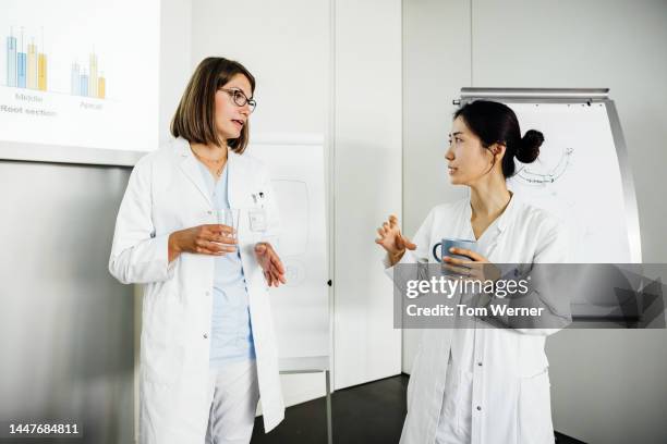 two senior dentist talking over cup of coffee in class - zwei zahnärzte stock-fotos und bilder