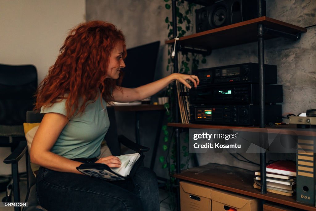 A smiling millennial woman listens to old music CDs