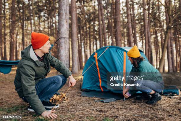 due campeggiatori montano una tenda e non vedono l'ora di trascorrere una giornata nella natura - picchetto da tenda foto e immagini stock