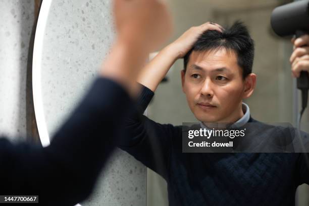 asian man drying hair reflecting on mirror - blow drying hair stock pictures, royalty-free photos & images