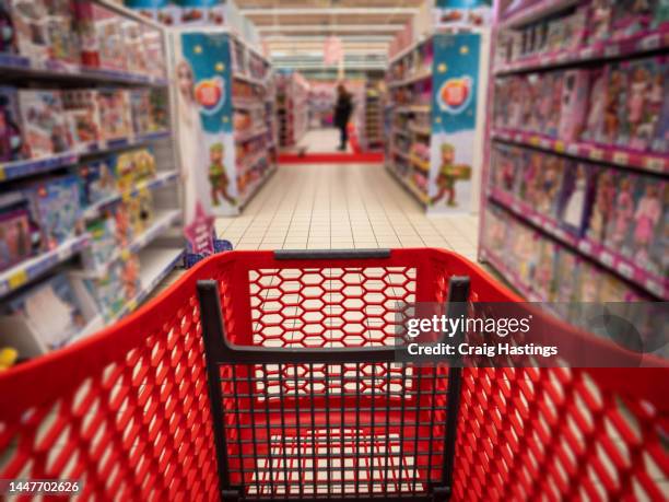 personal perspective of a shopper pushing shopping trolley along product aisle while shopping in a supermarket. super market children's toys and games aisle with blurred shelves and products to make it generic. - giocattoli foto e immagini stock