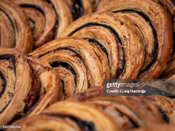 freshly baked cinnamon swirl bun sweet pastry treats close up. group of bread and pastry items stacked together on supermarket shelf in a large group - bread close up stock-fotos und bilder