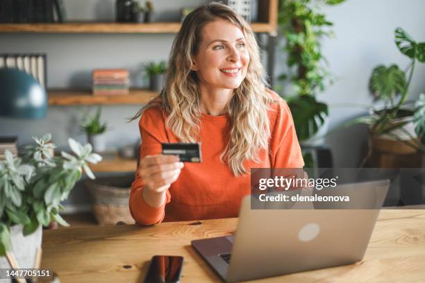 mature adult woman working at home (laptop ,credit card) - blank greeting card stockfoto's en -beelden