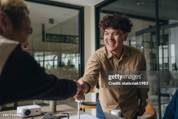smiling colleagues shaking hands in the office - transgender stock pictures, royalty-free photos & images