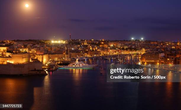 high angle view of illuminated buildings by river against sky at night,valletta,malta - modern malta stock pictures, royalty-free photos & images