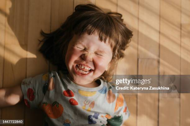 funny smiling toddler laying on the floor in sun raysin - childhood development stock pictures, royalty-free photos & images