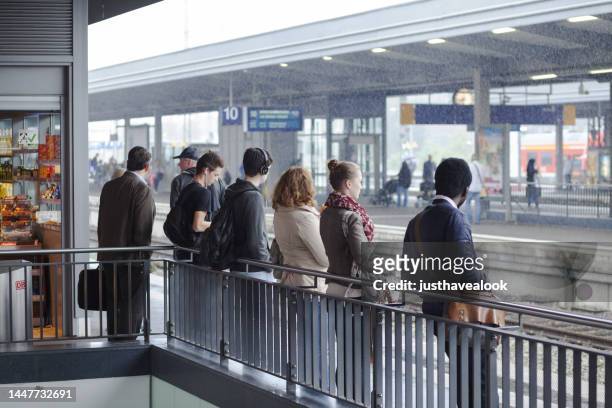 adults and commuters are waiting and leaning at railing in railroad station essen - essen germany bildbanksfoton och bilder