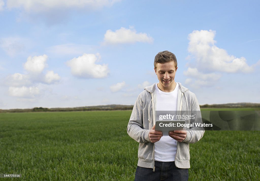 Man in countryside using digital tablet.