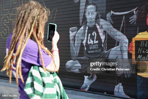 Phoenix Mercury fan Carley Givens takes a photo of a "Black Lives Matter" mural depicting Brittney Griner outside the Footprint Center on December...