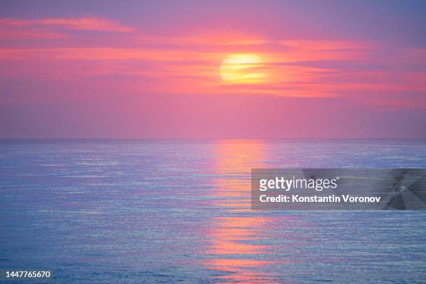 sunset over the sea. large solar disk behind the clouds. - abstract seascape stock pictures, royalty-free photos & images