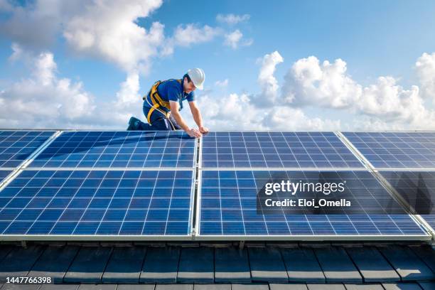 professioneller arbeiter, der sonnenkollektoren auf dem dach eines hauses installiert - sonnenkollektor stock-fotos und bilder