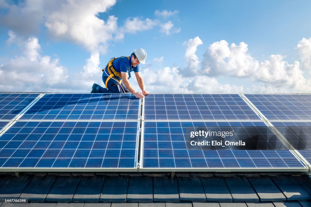 Professional worker installing solar panels on the roof of a house
