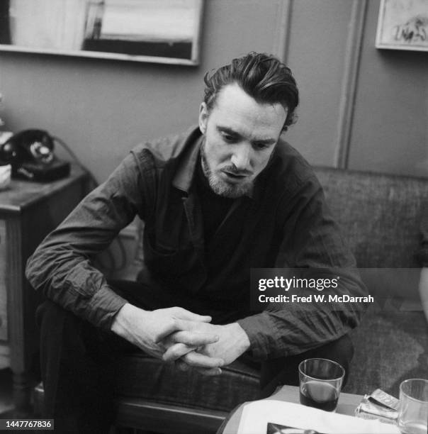 American writer Lew Welch sits on a couch in the apartment of photographer Fred McDarrah and his soon-to-be wife, Gloria, New York, New York,...