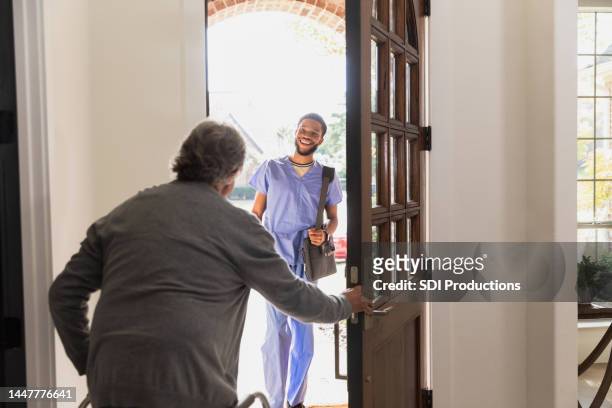 senior man welcomes home health nurse - answering door stock pictures, royalty-free photos & images