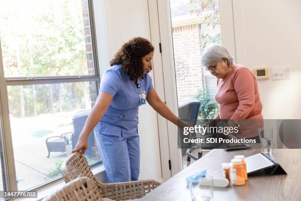 krankenschwester hilft patientin, am tisch zu sitzen - rollator stock-fotos und bilder