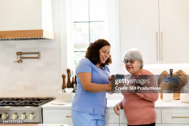 home healthcare nurse helps senior patient with smart phone - showing empathy stock pictures, royalty-free photos & images