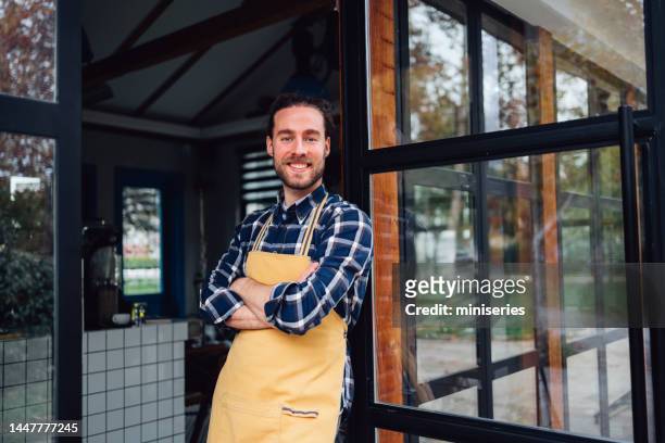 handsome barista leaning on the care doorway - dag 1 stockfoto's en -beelden