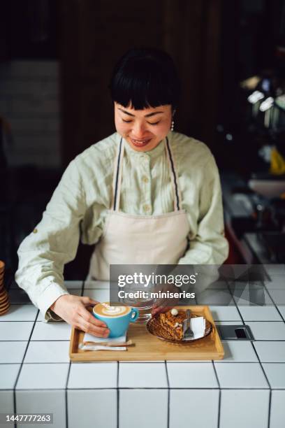 hermosa mujer asiática feliz poniendo una taza de café en una bandeja - préparation dessert fotografías e imágenes de stock