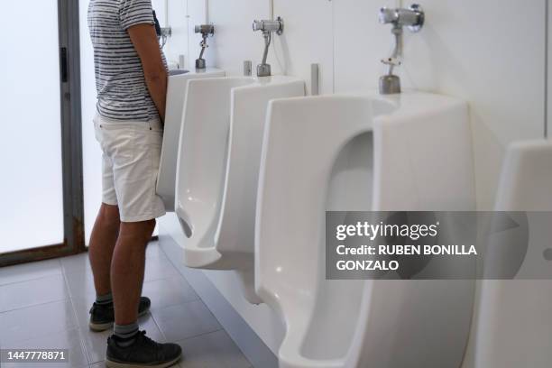 man using urinal in public bathroom. - urine stockfoto's en -beelden
