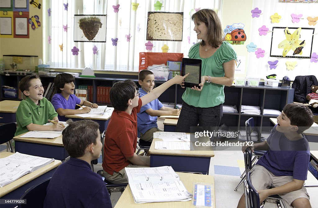 Teacher using tablet computer / tablet to teach kids in class