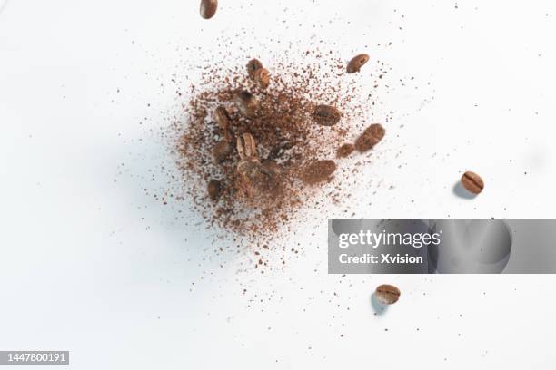 coffee beans with coffee powder flying in mid air in white background - coffee slow motion stock pictures, royalty-free photos & images