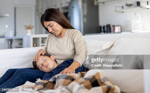 liebevolle mutter verwöhnt ihren kranken sohn, während er schläft - krank stock-fotos und bilder